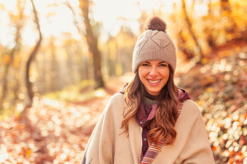 Жена шета кроз шуму сунчаног јесењег дана